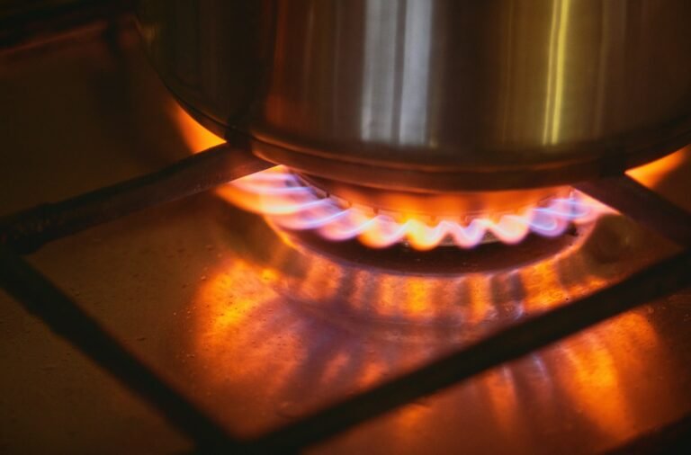 A pot cooking on a lit gas stove burner in a home kitchen
