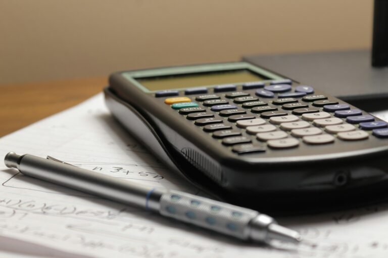 Calculator, pen and business records on a desk for tracking sales and expenses