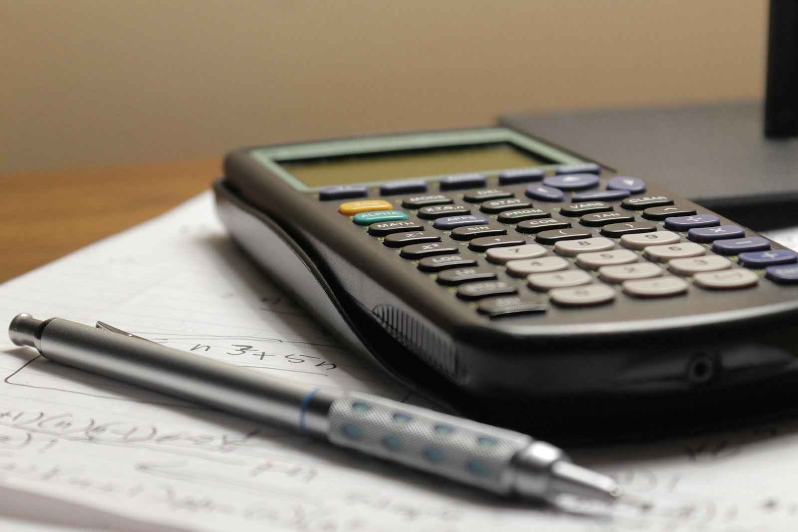 Calculator, pen and business records on a desk for tracking sales and expenses