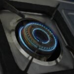 Close-up of a gas cooker burner with a blue flame